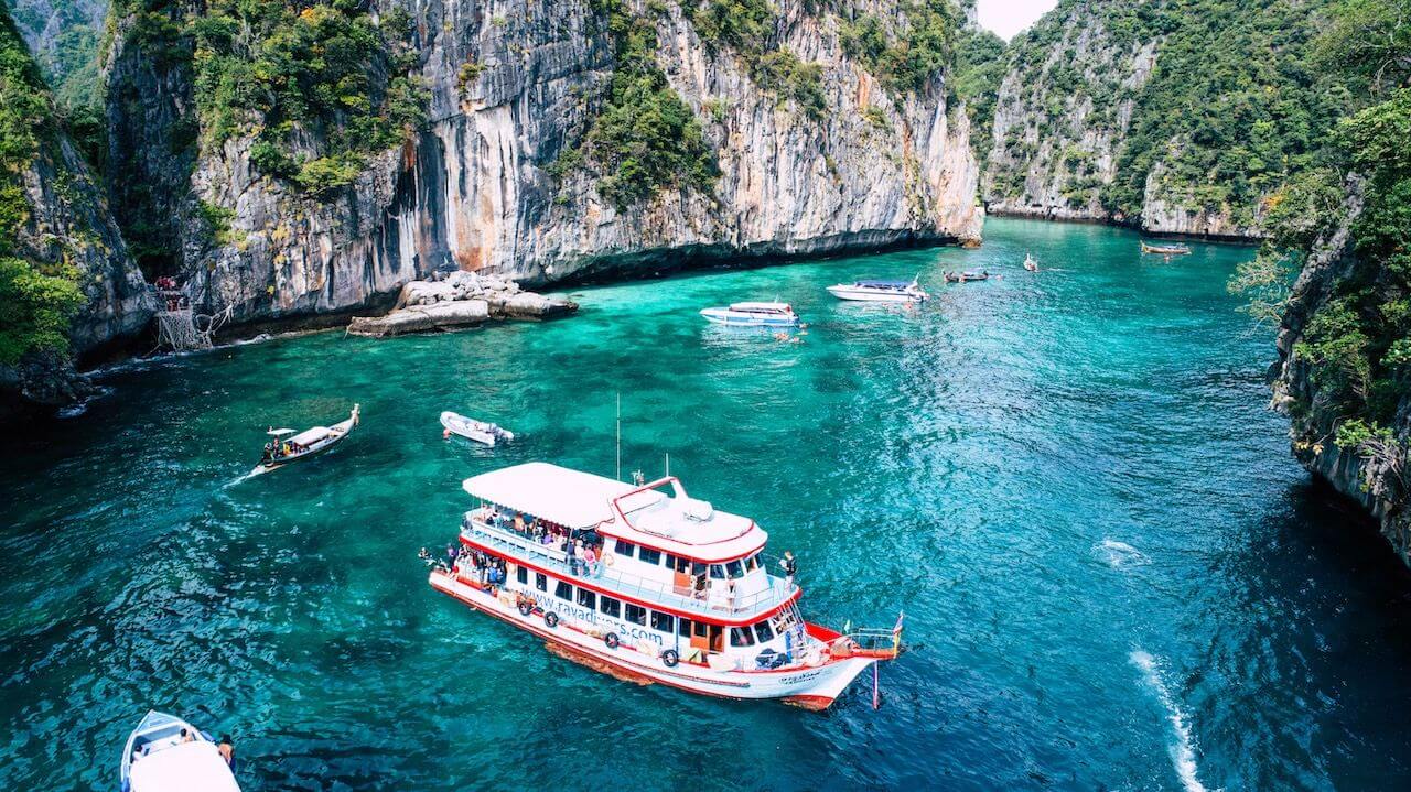 Ilmakuva Koh Phi Phin kalkkikivikallioiden ympäröimästä turkoosista lahdesta ja retkiveneestä